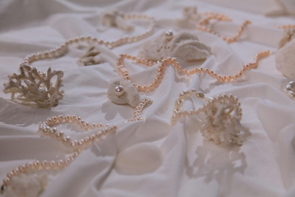 Sophisticated pearl necklaces elegantly draped on coral, signifying luxury and nature's beauty.